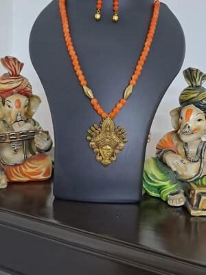 Orange glass beads necklace with oxidised golden Durga pendant and matching earrings